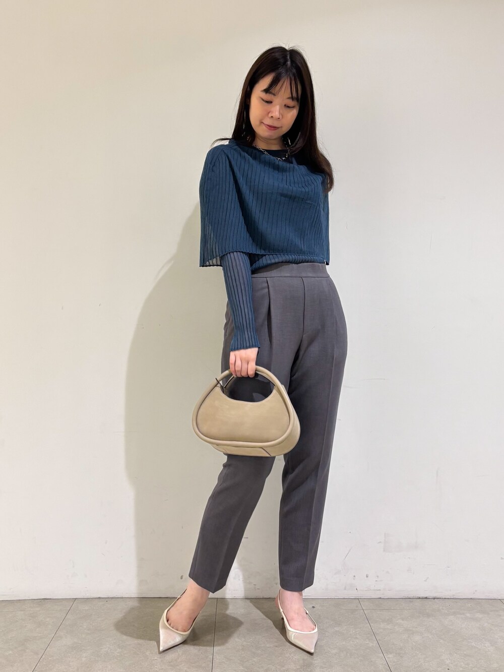 ブルー系のニット/セーター、グレー系のスラックスを着用したレディースの秋コーディネートの3枚目の写真