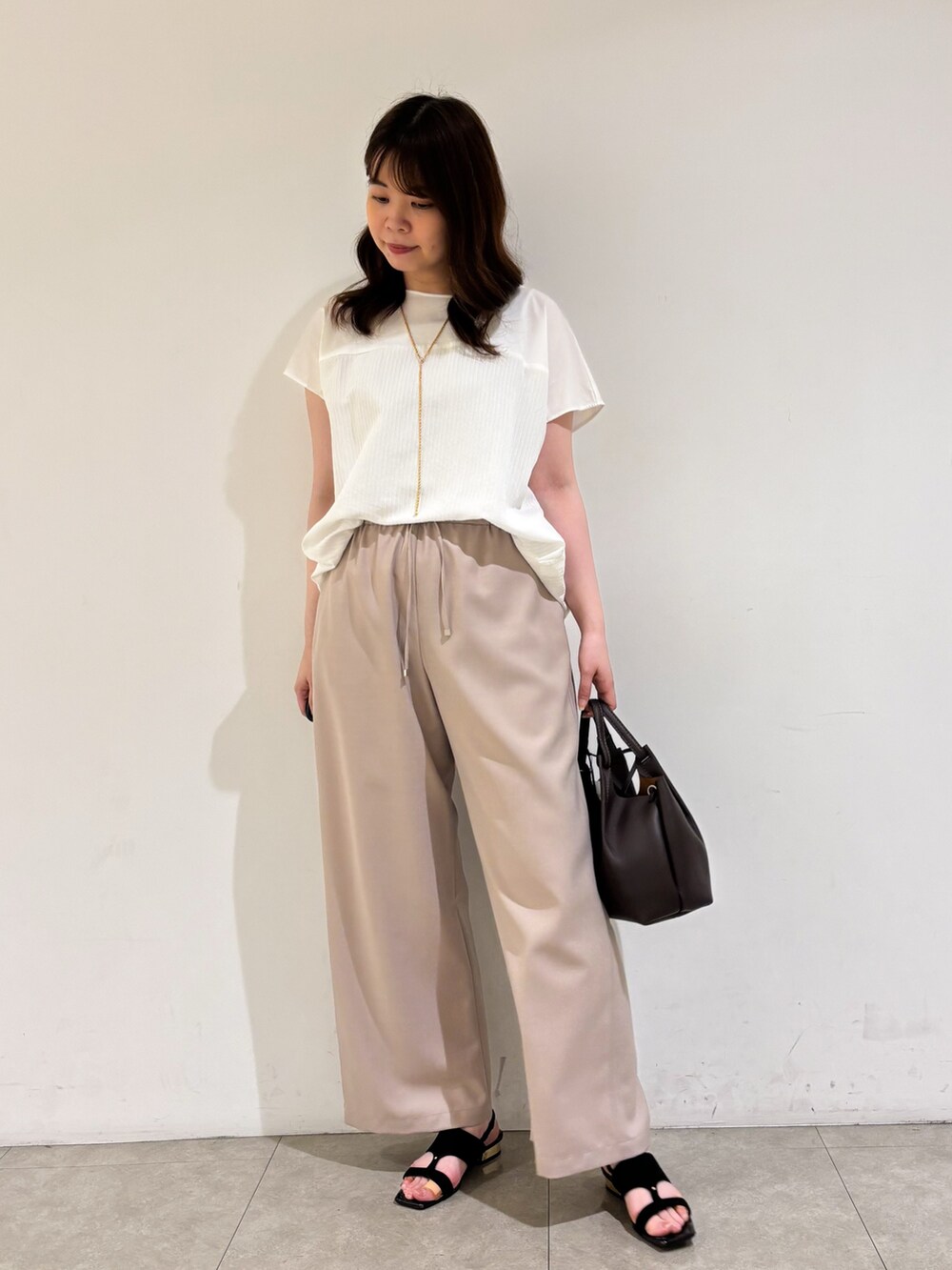 ホワイト系のTシャツ/カットソー、ベージュ系のその他パンツ、ブラック系のサンダルを着用したレディースの夏コーディネートの3枚目の写真