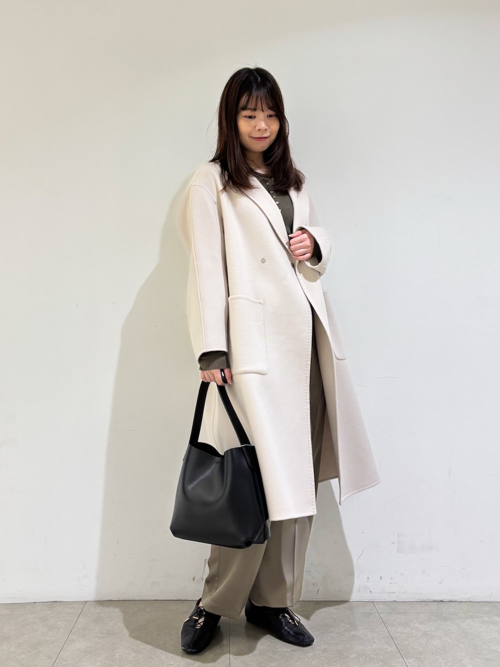 ベージュ系のチェスターコート、ブラウン系のニット/セーター、グリーン系のその他パンツを着用したレディースの秋コーディネートの2枚目の写真