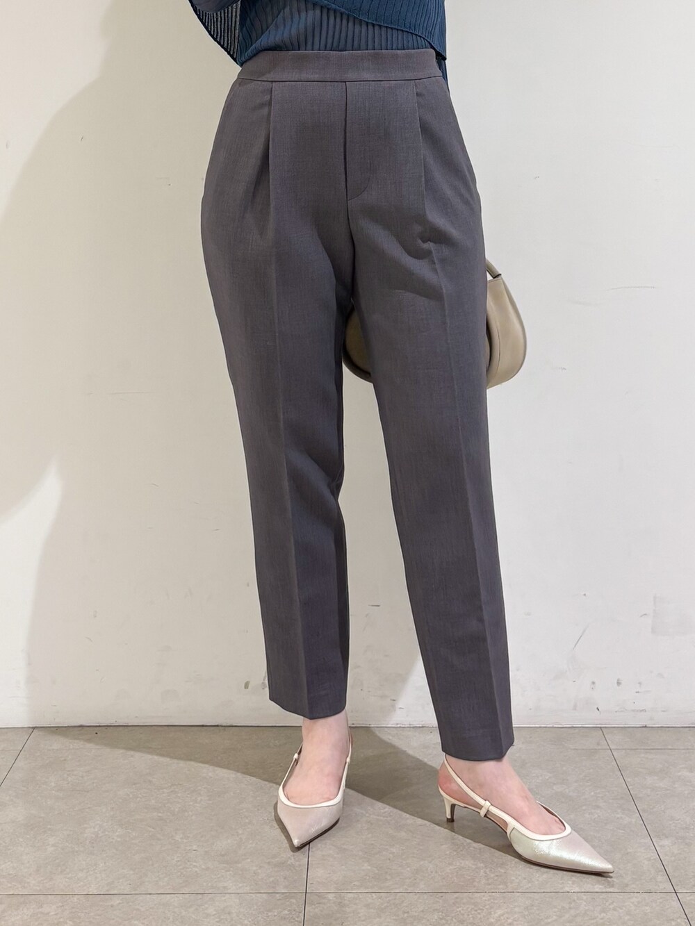 ブルー系のニット/セーター、グレー系のスラックスを着用したレディースの秋コーディネートの8枚目の写真