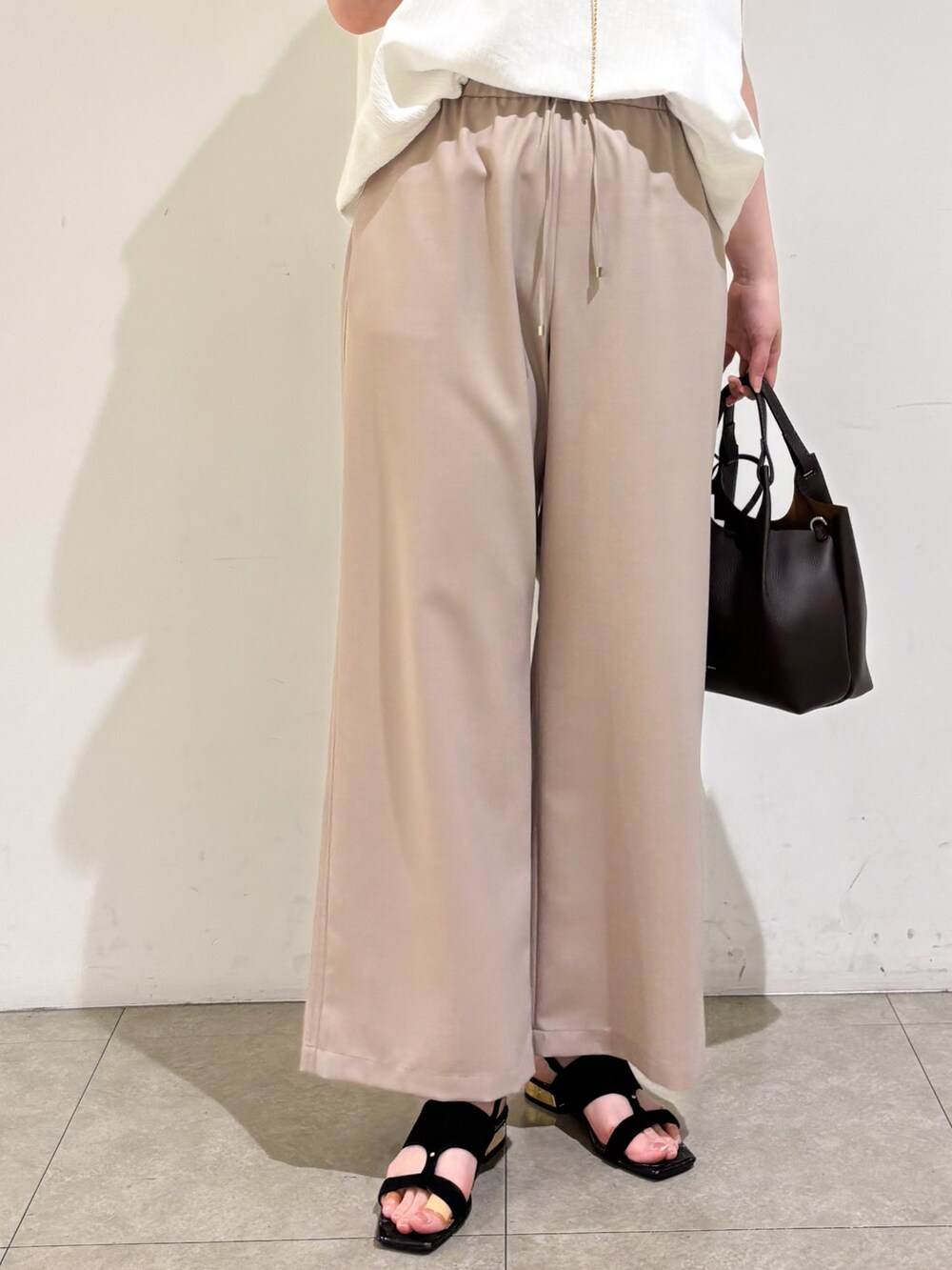 ホワイト系のTシャツ/カットソー、ベージュ系のその他パンツ、ブラック系のサンダルを着用したレディースの夏コーディネートの9枚目の写真
