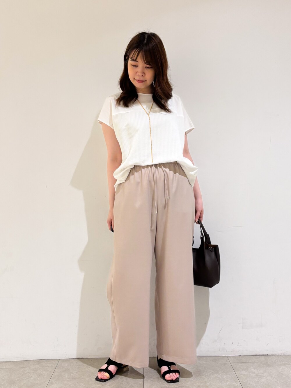 ホワイト系のTシャツ/カットソー、ベージュ系のその他パンツ、ブラック系のサンダルを着用したレディースの夏コーディネートの2枚目の写真