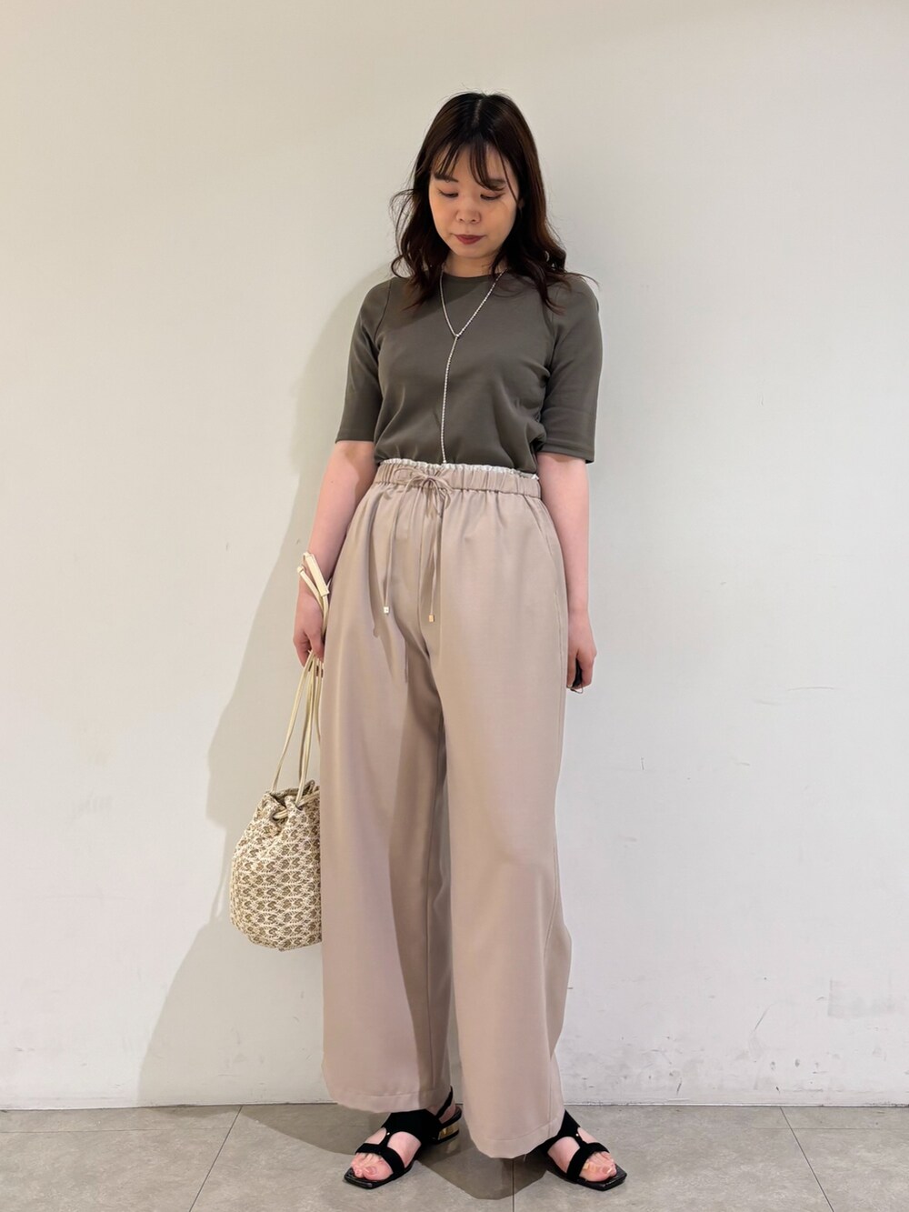 ベージュ系のその他パンツ、ホワイト系のショルダーバッグ、ブラック系のサンダルを着用したレディースの夏コーディネートの3枚目の写真