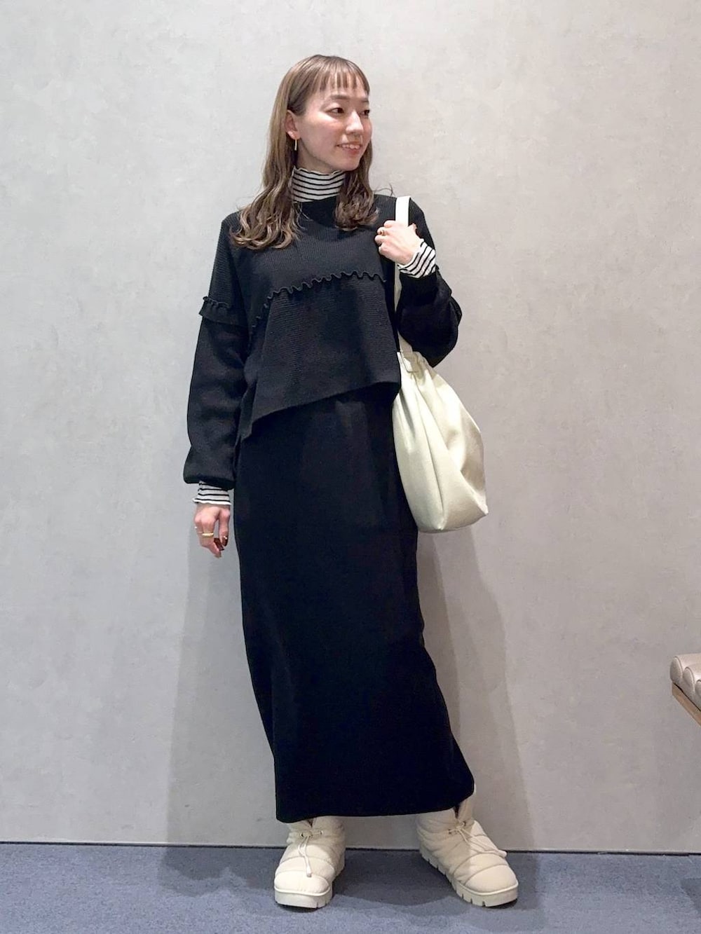 ホワイト系のショルダーバッグ、ブラック系のワンピース、ホワイト系のTシャツ/カットソーを着用したレディースの冬コーディネートの2枚目の写真