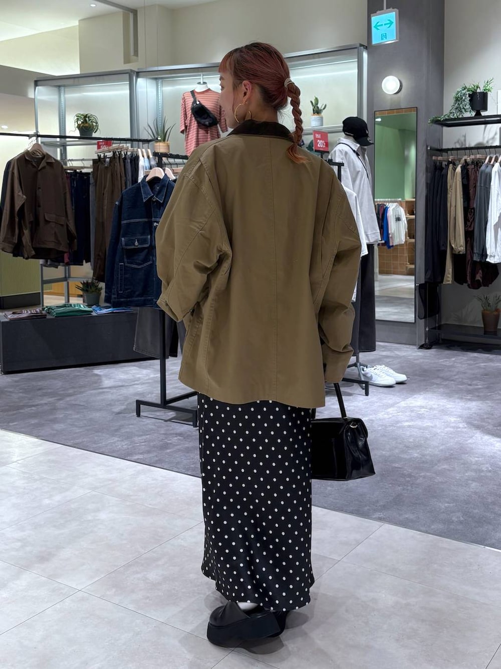 ブラック系のスカート、ブラウン系のブルゾン、ブラック系のボストンバッグを着用したレディースの秋コーディネートの5枚目の写真