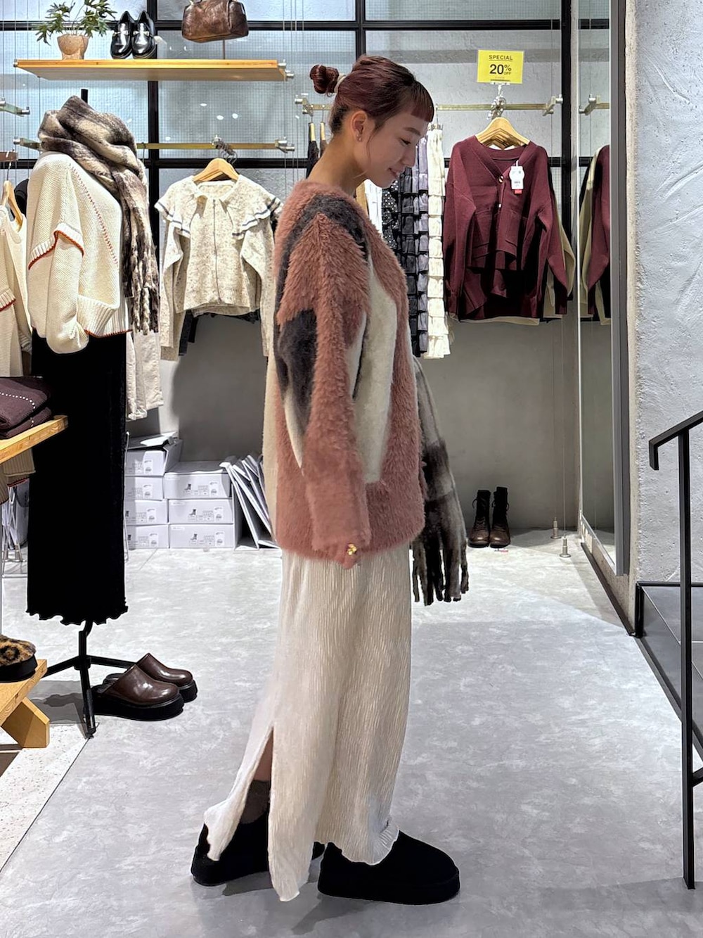 ピンク系のカーディガン/ボレロ、ゴールド系のタンクトップ、ホワイト系のスカートを着用したレディースの秋コーディネートの3枚目の写真