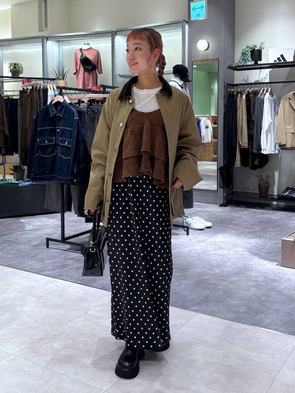 ブラック系のスカート、ブラウン系のブルゾン、ブラック系のボストンバッグを着用したレディースの秋コーディネートの2枚目の写真