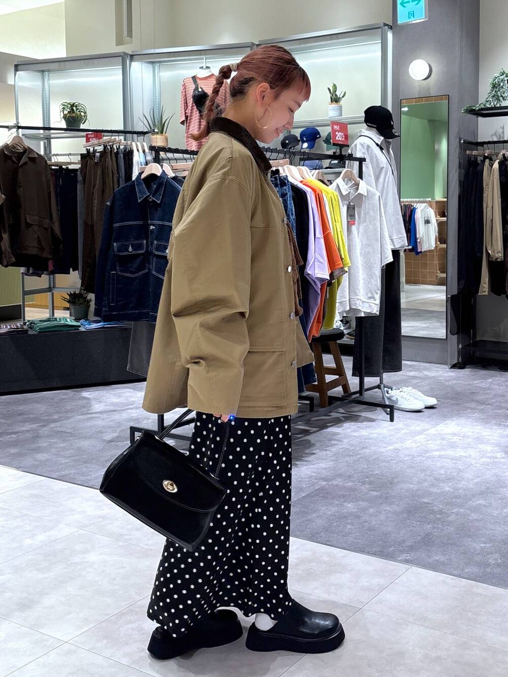 ブラック系のスカート、ブラウン系のブルゾン、ブラック系のボストンバッグを着用したレディースの秋コーディネートの3枚目の写真