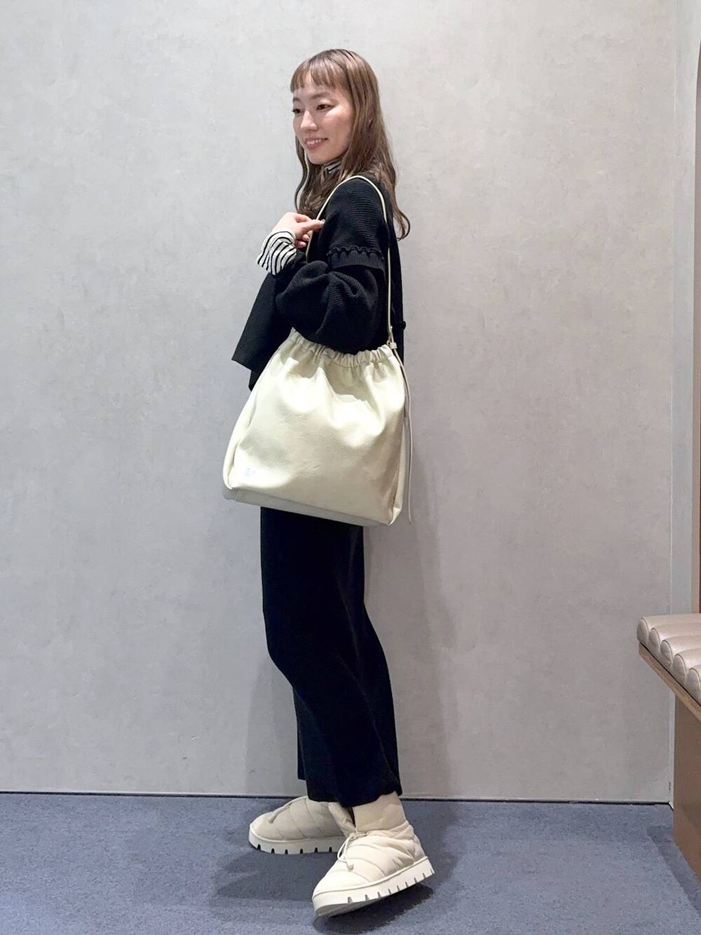 ホワイト系のショルダーバッグ、ブラック系のワンピース、ホワイト系のTシャツ/カットソーを着用したレディースの冬コーディネートの4枚目の写真