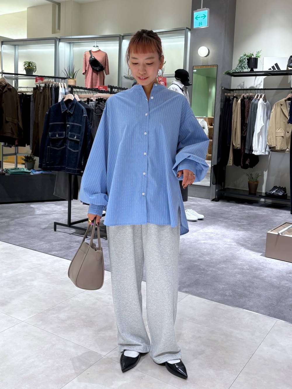 ブルー系のシャツ/ブラウス、グレー系のショルダーバッグ、ブラック系のパンプスを着用したレディースの秋コーディネートの2枚目の写真