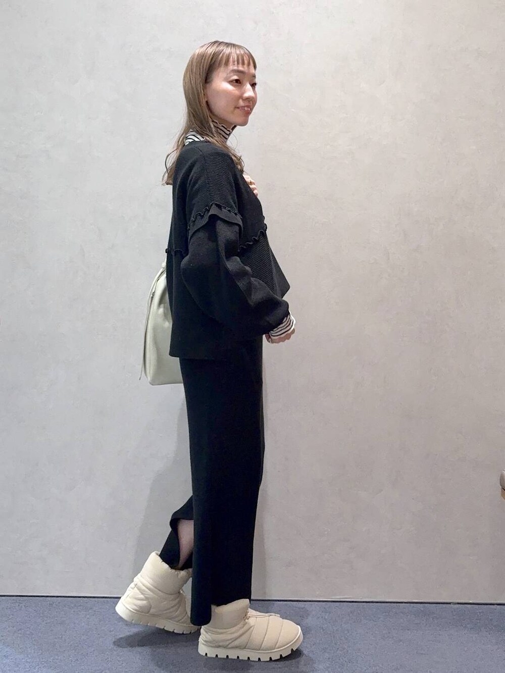 ホワイト系のショルダーバッグ、ブラック系のワンピース、ホワイト系のTシャツ/カットソーを着用したレディースの冬コーディネートの3枚目の写真