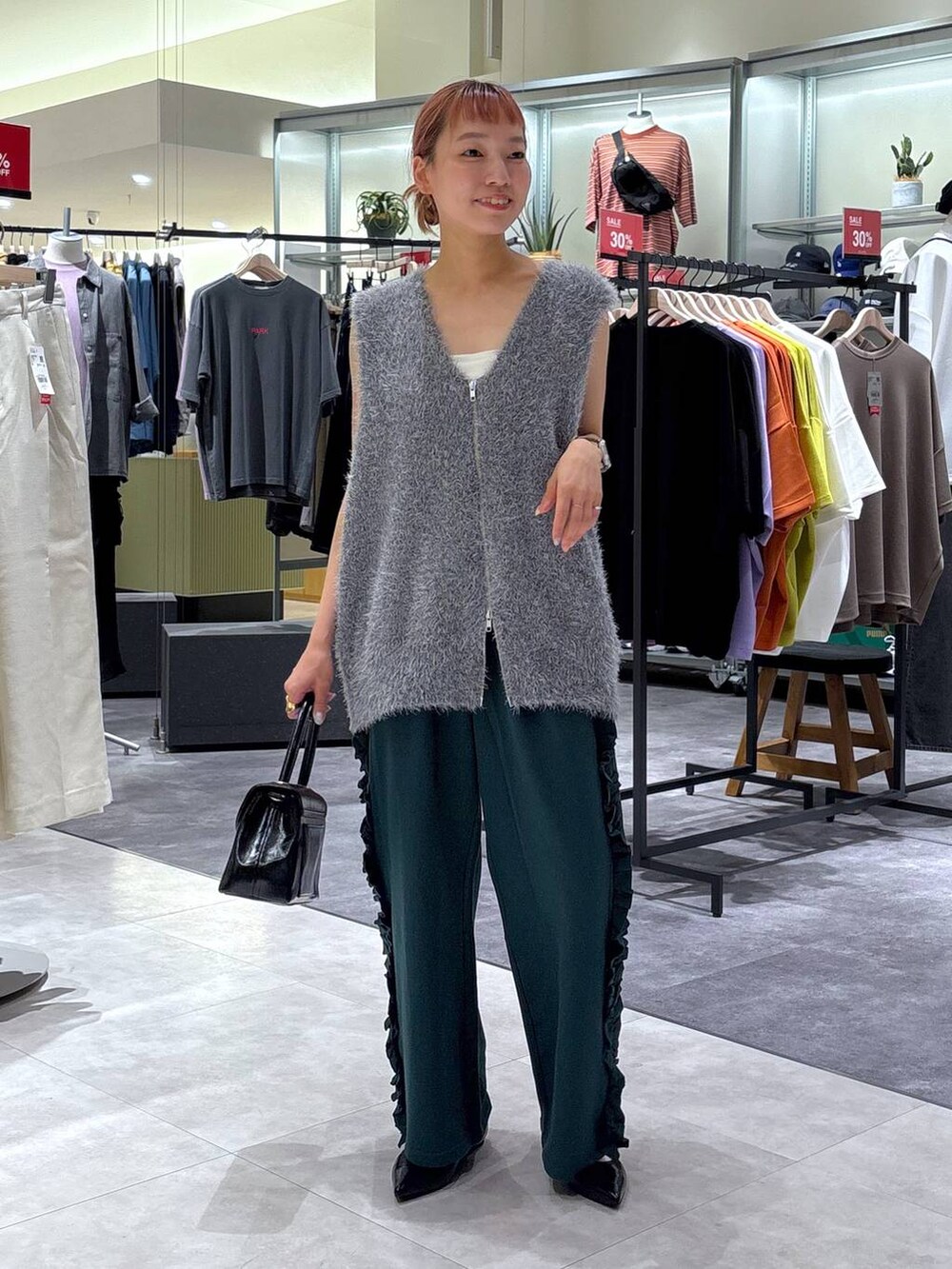 ブラック系のボストンバッグ、グリーン系のスウェットパンツ、グレー系のベストを着用したレディースの秋コーディネートの2枚目の写真