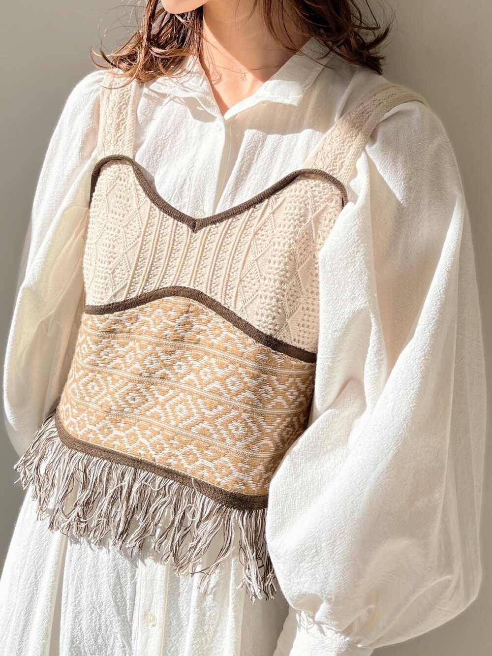 ベージュ系のベスト、ホワイト系のワンピースを着用したレディースの冬コーディネートの4枚目の写真