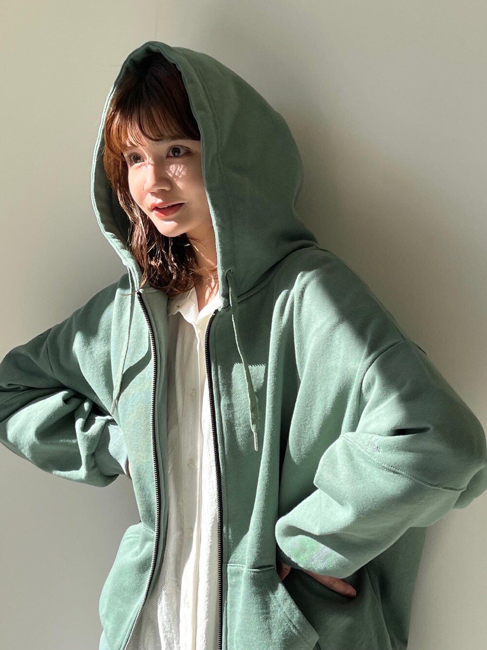 グリーン系のパーカー、ホワイト系のワンピースを着用したレディースの冬コーディネートの2枚目の写真