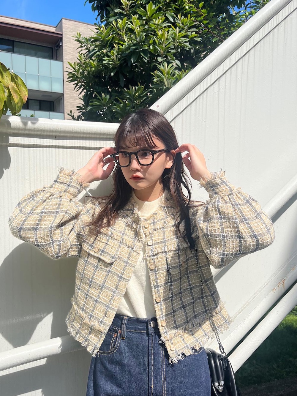 ブラック系のデニムパンツ、ホワイト系のショルダーバッグ、ベージュ系のノーカラージャケットを着用したレディースの秋コーディネートの2枚目の写真