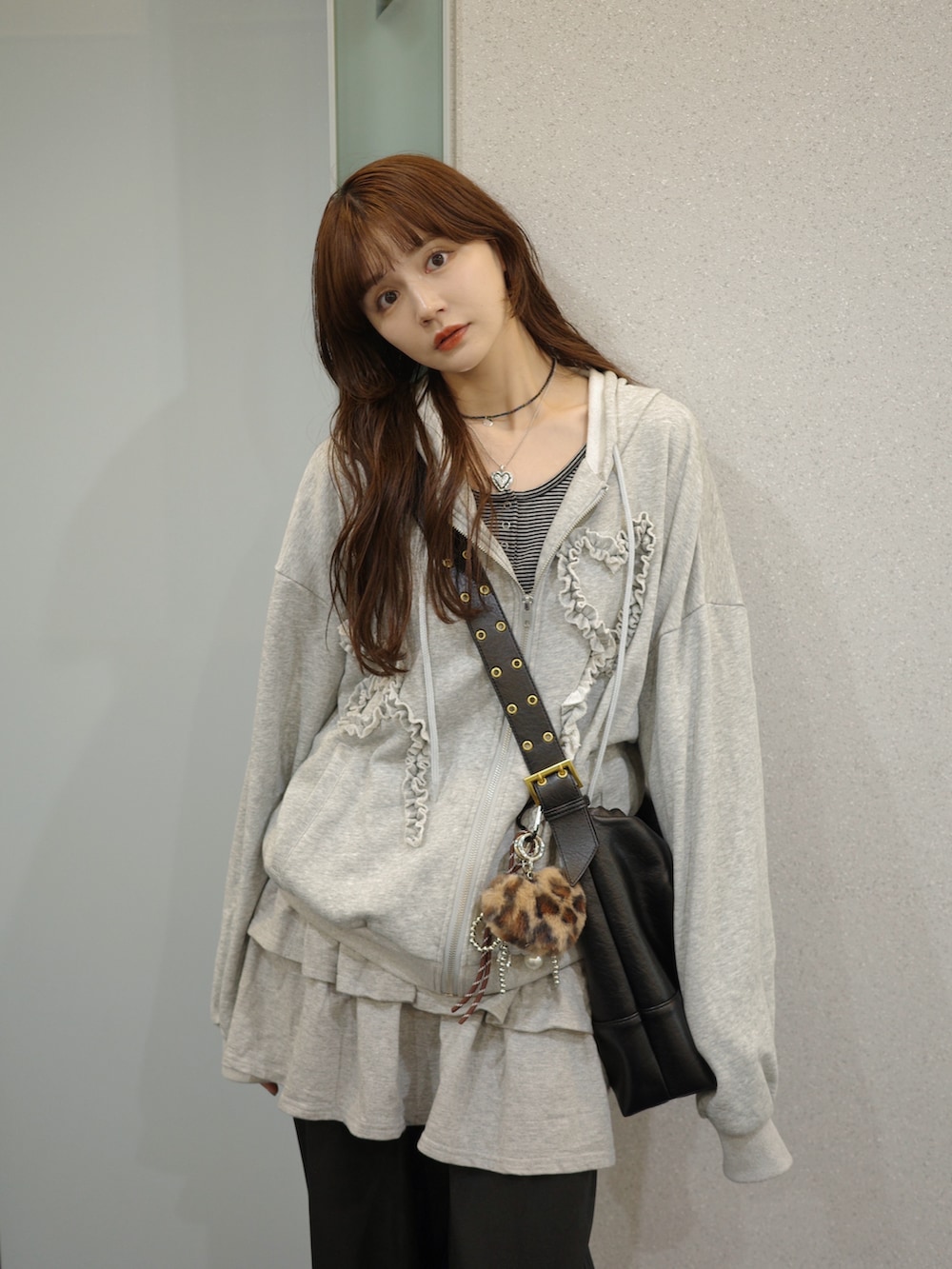 ブラック系のショルダーバッグ、グレー系のパーカー、ブラック系のスラックスを着用したレディースの春コーディネートの2枚目の写真