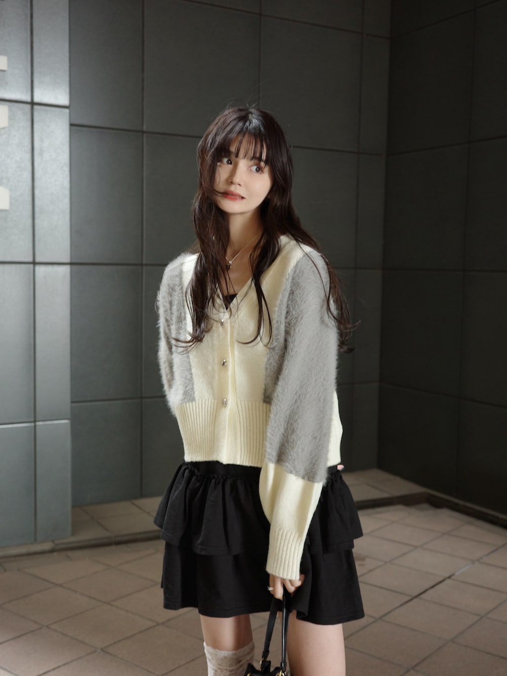 ホワイト系のカーディガン/ボレロ、ブラック系のスカート、ブラック系のローファーを着用したレディースの秋コーディネートの2枚目の写真