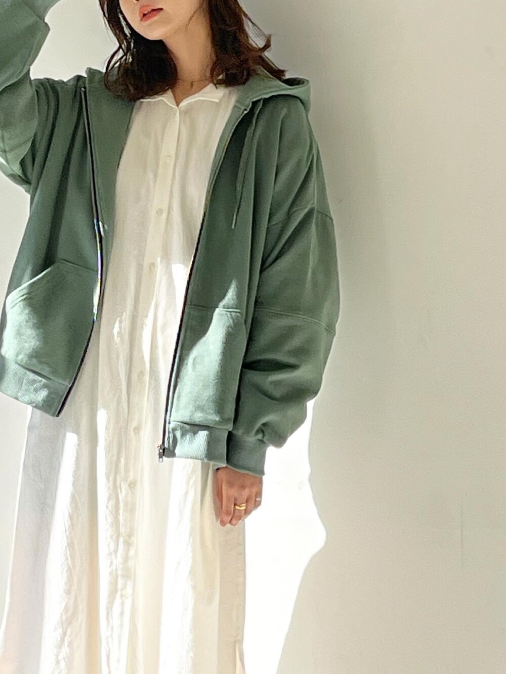 グリーン系のパーカー、ホワイト系のワンピースを着用したレディースの冬コーディネートの3枚目の写真