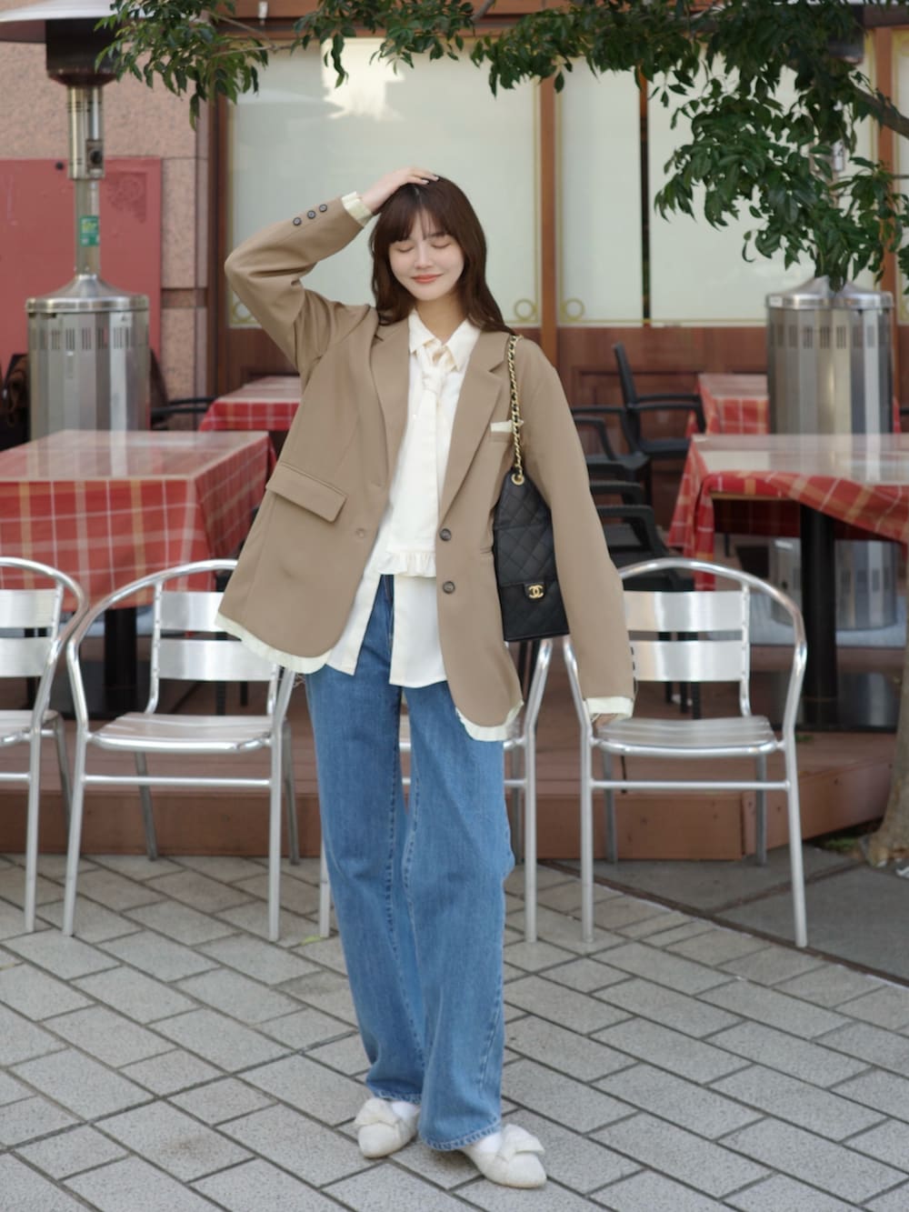 グレー系のテーラードジャケット、ホワイト系のシャツ/ブラウス、ブルー系のデニムパンツを着用したレディースの冬コーディネートの2枚目の写真