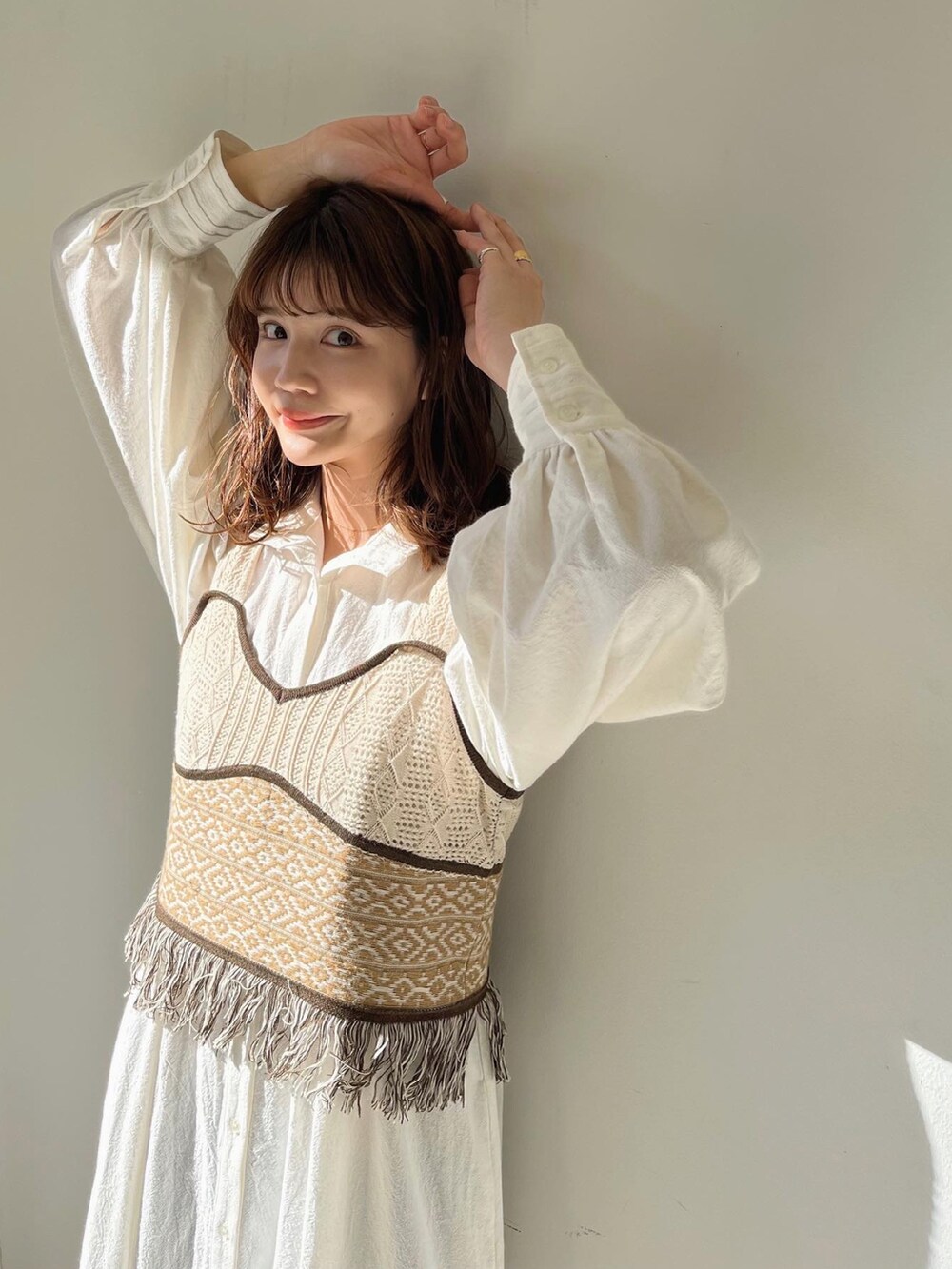 ベージュ系のベスト、ホワイト系のワンピースを着用したレディースの冬コーディネートの2枚目の写真