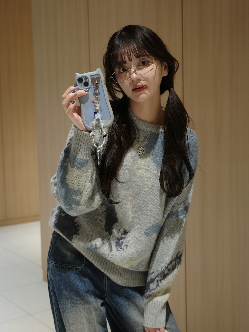 グレー系のニット/セーター、ブルー系のデニムパンツ、ホワイト系のショルダーバッグを着用したレディースの秋コーディネートの3枚目の写真