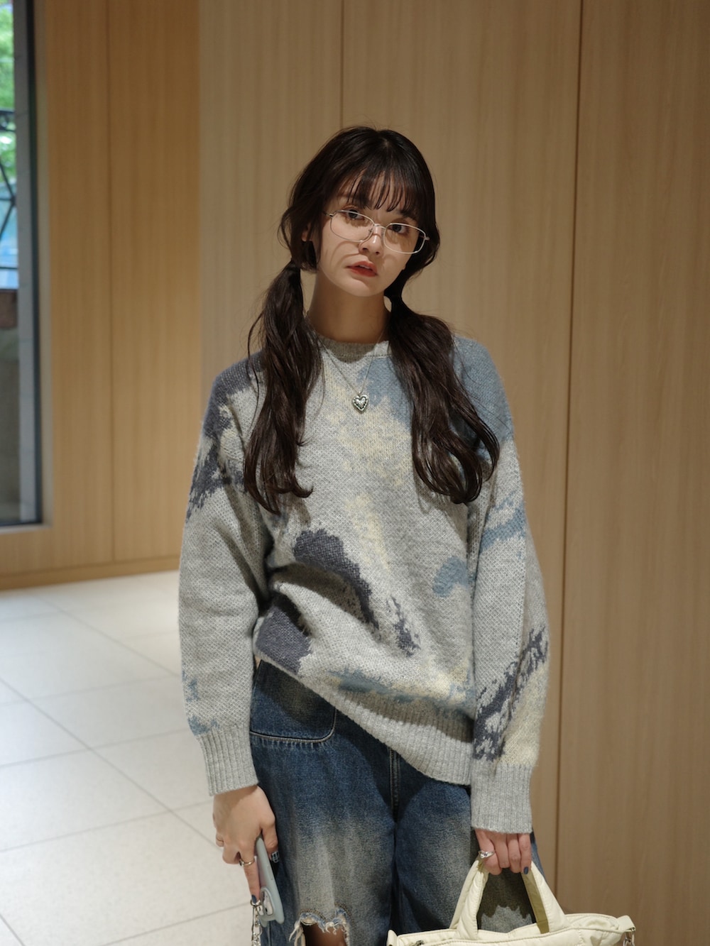 グレー系のニット/セーター、ブルー系のデニムパンツ、ホワイト系のショルダーバッグを着用したレディースの秋コーディネートの2枚目の写真