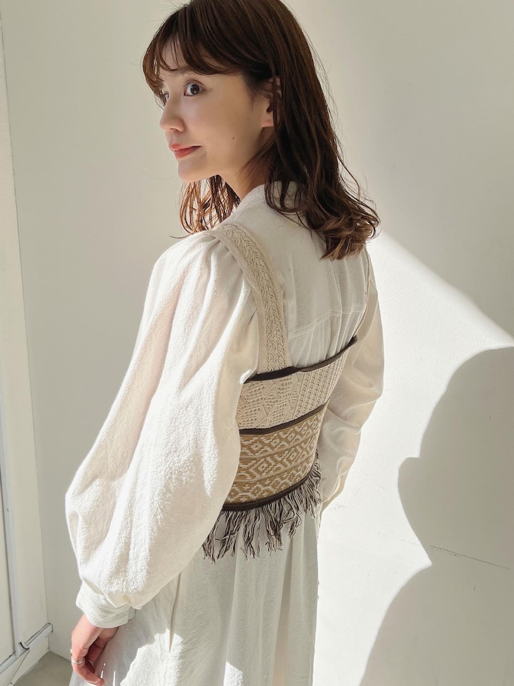 ベージュ系のベスト、ホワイト系のワンピースを着用したレディースの冬コーディネートの3枚目の写真