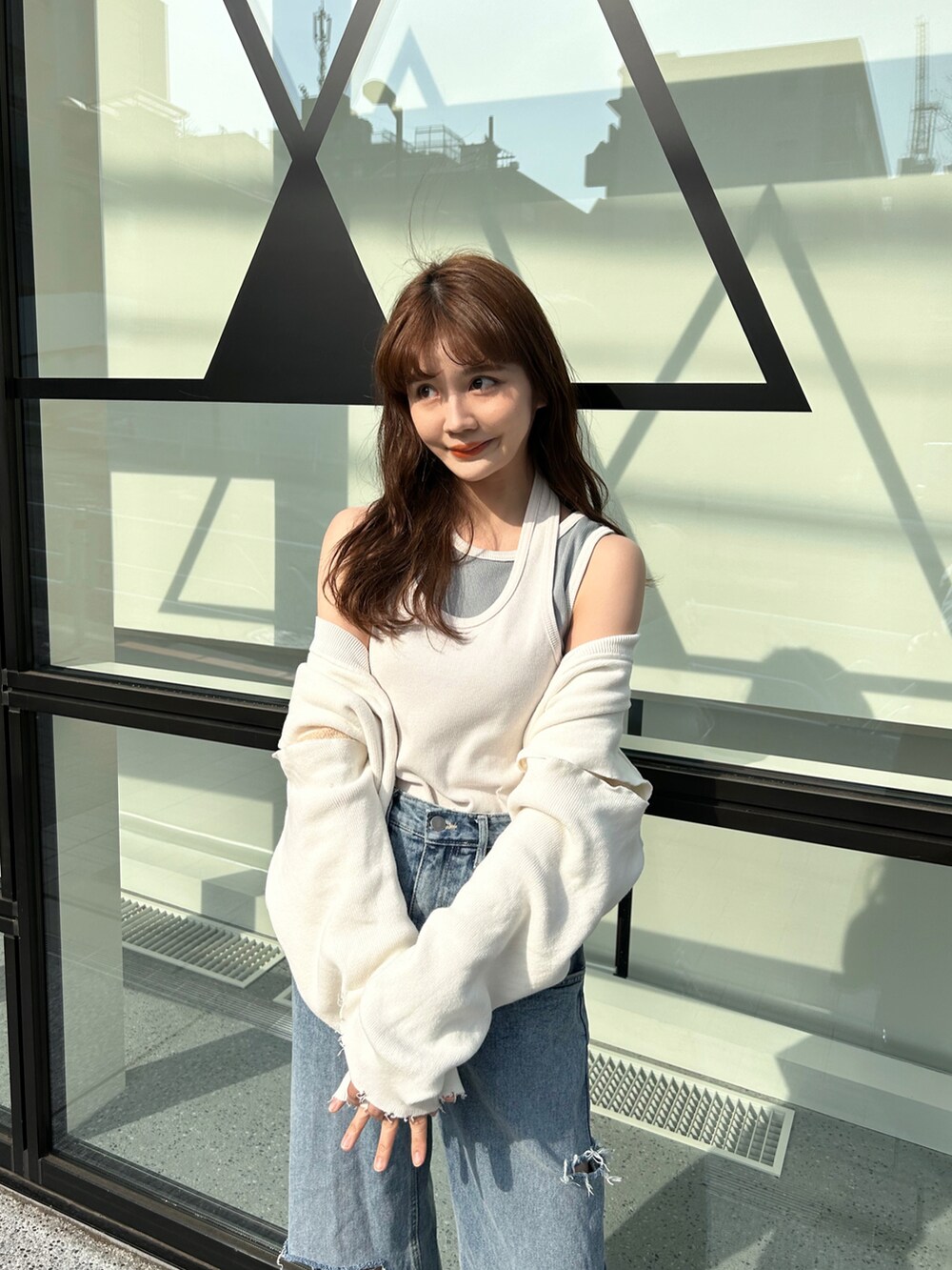 ホワイト系のタンクトップ、ブルー系のデニムパンツ、ホワイト系のサンダルを着用したレディースの春コーディネートの2枚目の写真