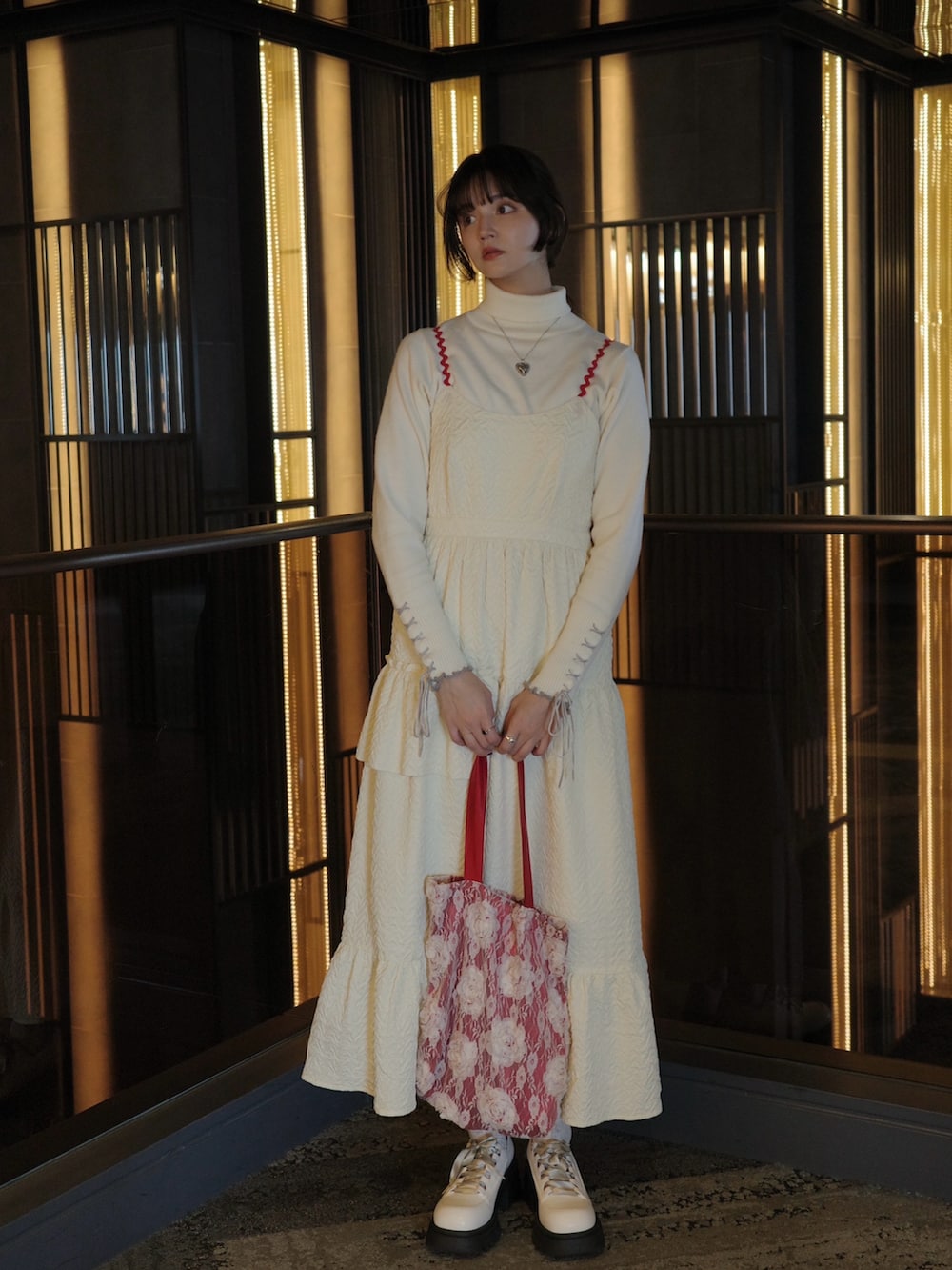 ホワイト系のワンピース、レッド系のトートバッグ、ホワイト系のニット/セーターを着用したレディースの秋コーディネートの2枚目の写真