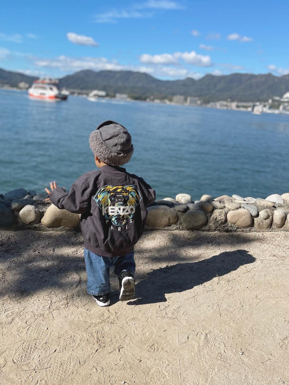 グレー系のブルゾン、ブルー系のサロペット/オーバーオール、ブラック系のスニーカーを着用したキッズの秋コーディネートの2枚目の写真