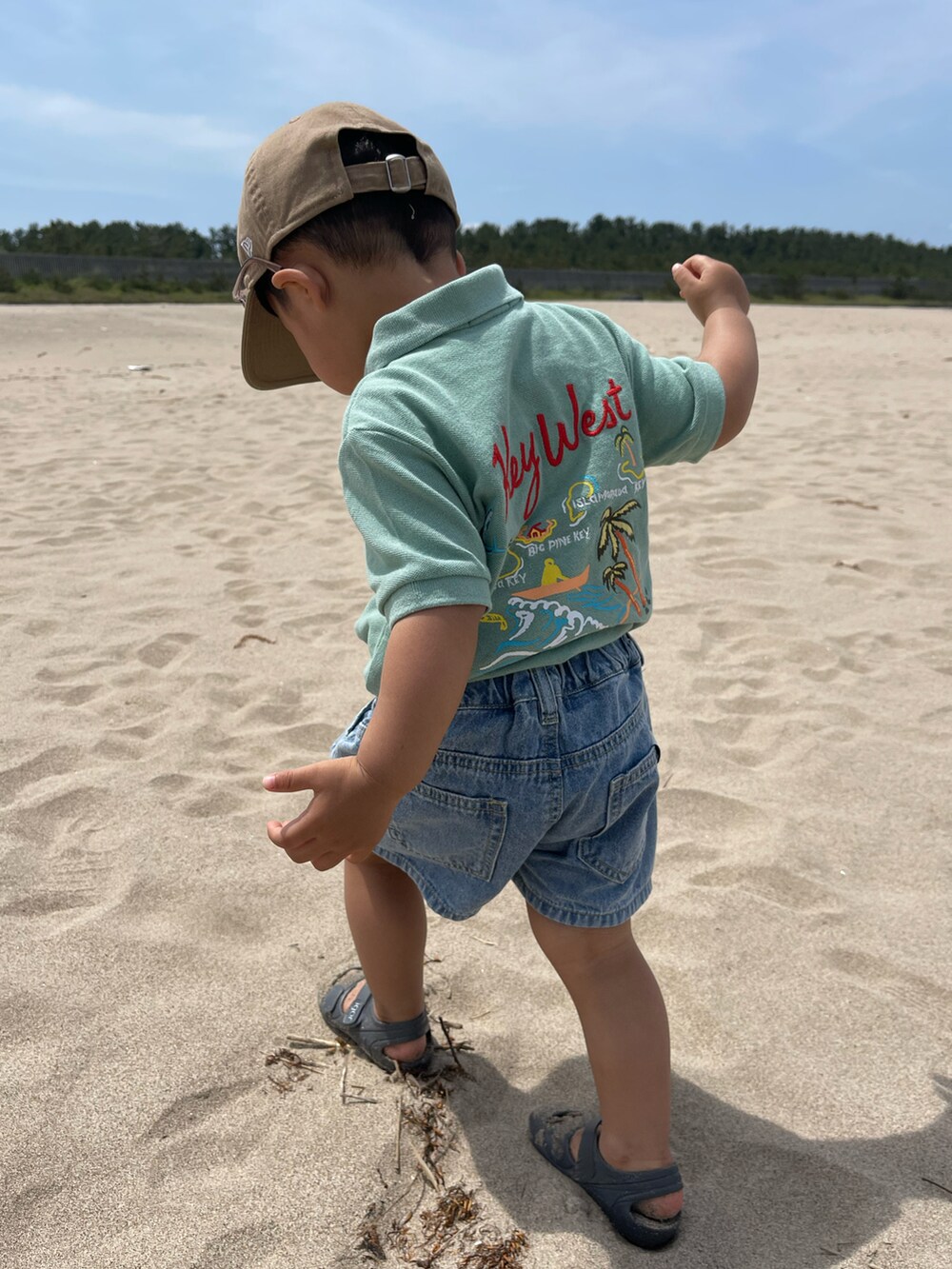 グリーン系のポロシャツ、ブルー系のデニムパンツ、ブルー系のサンダルを着用したキッズの春コーディネートの2枚目の写真