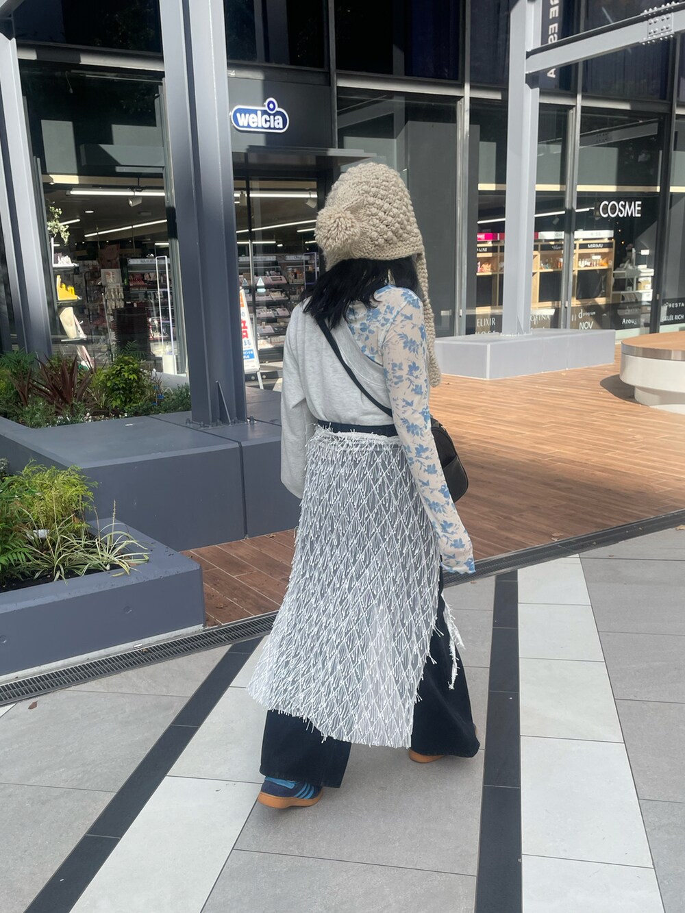 ブルー系のスニーカー、ブラック系のボストンバッグ、ブラック系のデニムパンツを着用したレディースの秋コーディネートの2枚目の写真