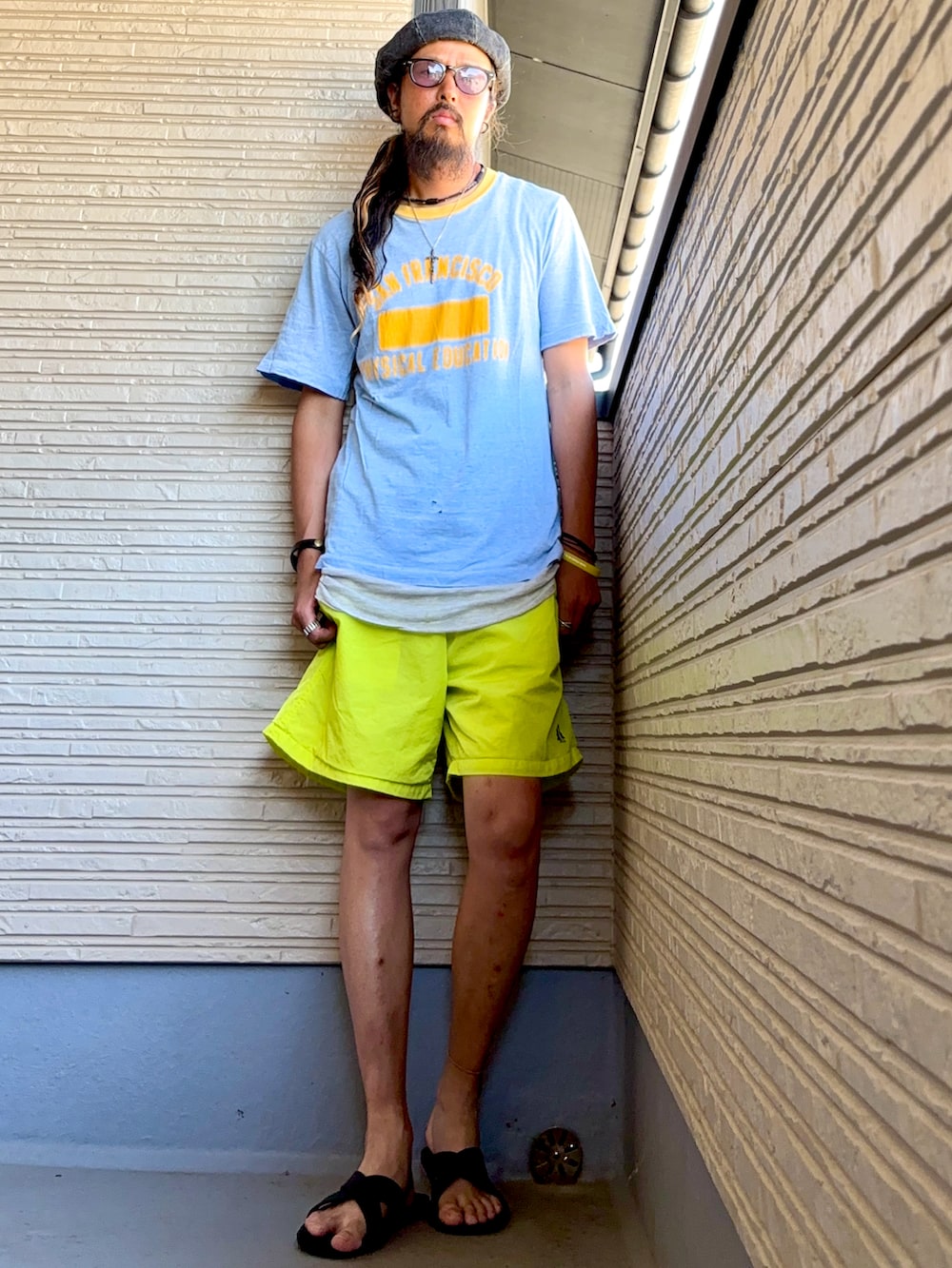 ブルー系のTシャツ/カットソー、イエロー系のその他パンツ、ブラック系のサンダルを着用したメンズの夏コーディネートの2枚目の写真