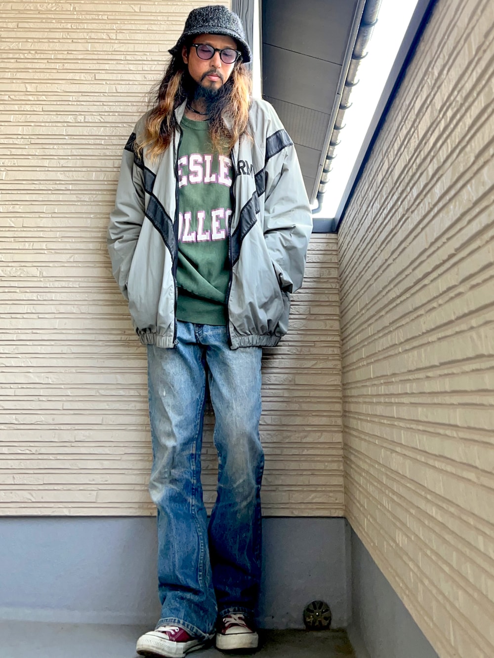 グレー系のミリタリージャケット、グリーン系のスウェット、ブルー系のデニムパンツを着用したメンズの秋コーディネートの2枚目の写真