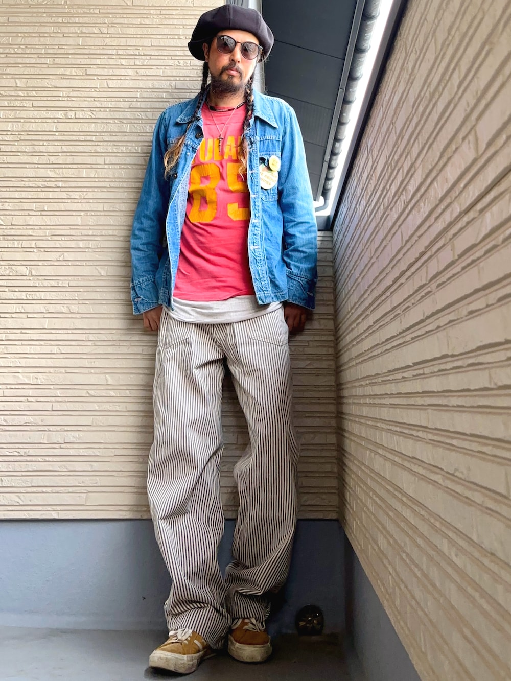 レッド系のTシャツ/カットソー、ブルー系のデニムジャケット、ベージュ系のパンツを着用したメンズの春コーディネートの3枚目の写真