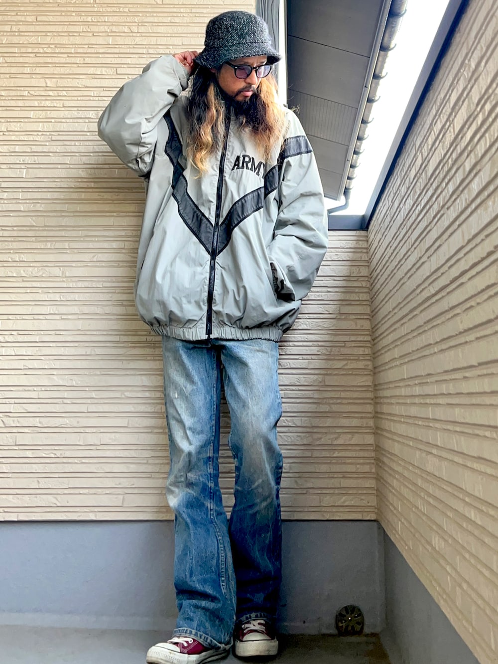 グレー系のミリタリージャケット、グリーン系のスウェット、ブルー系のデニムパンツを着用したメンズの秋コーディネートの3枚目の写真