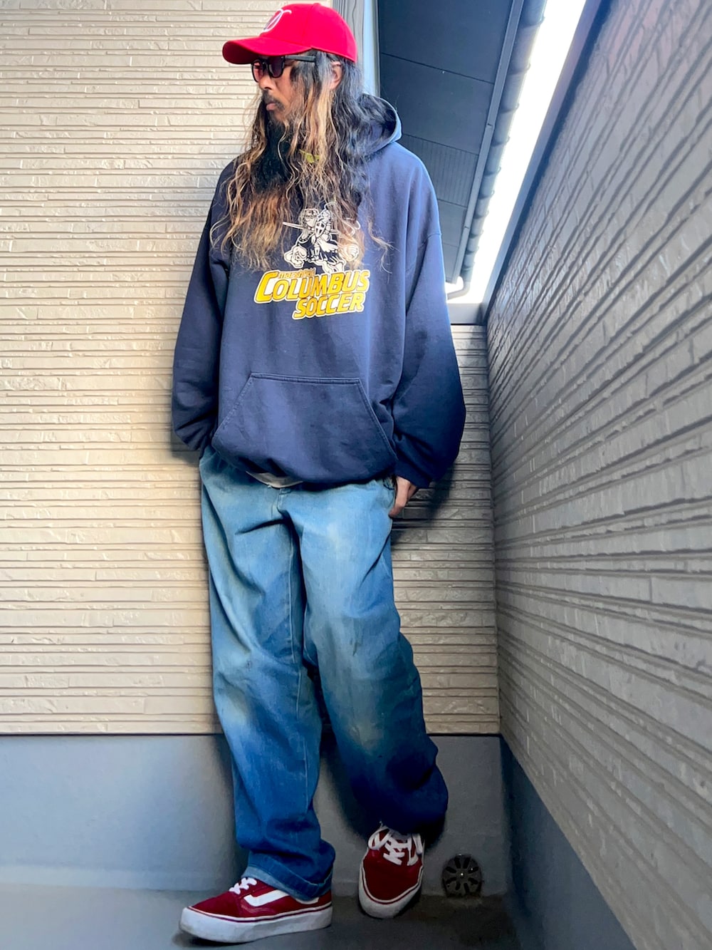 ブルー系のパーカー、ブルー系のデニムパンツ、レッド系のスニーカーを着用したメンズの冬コーディネートの5枚目の写真