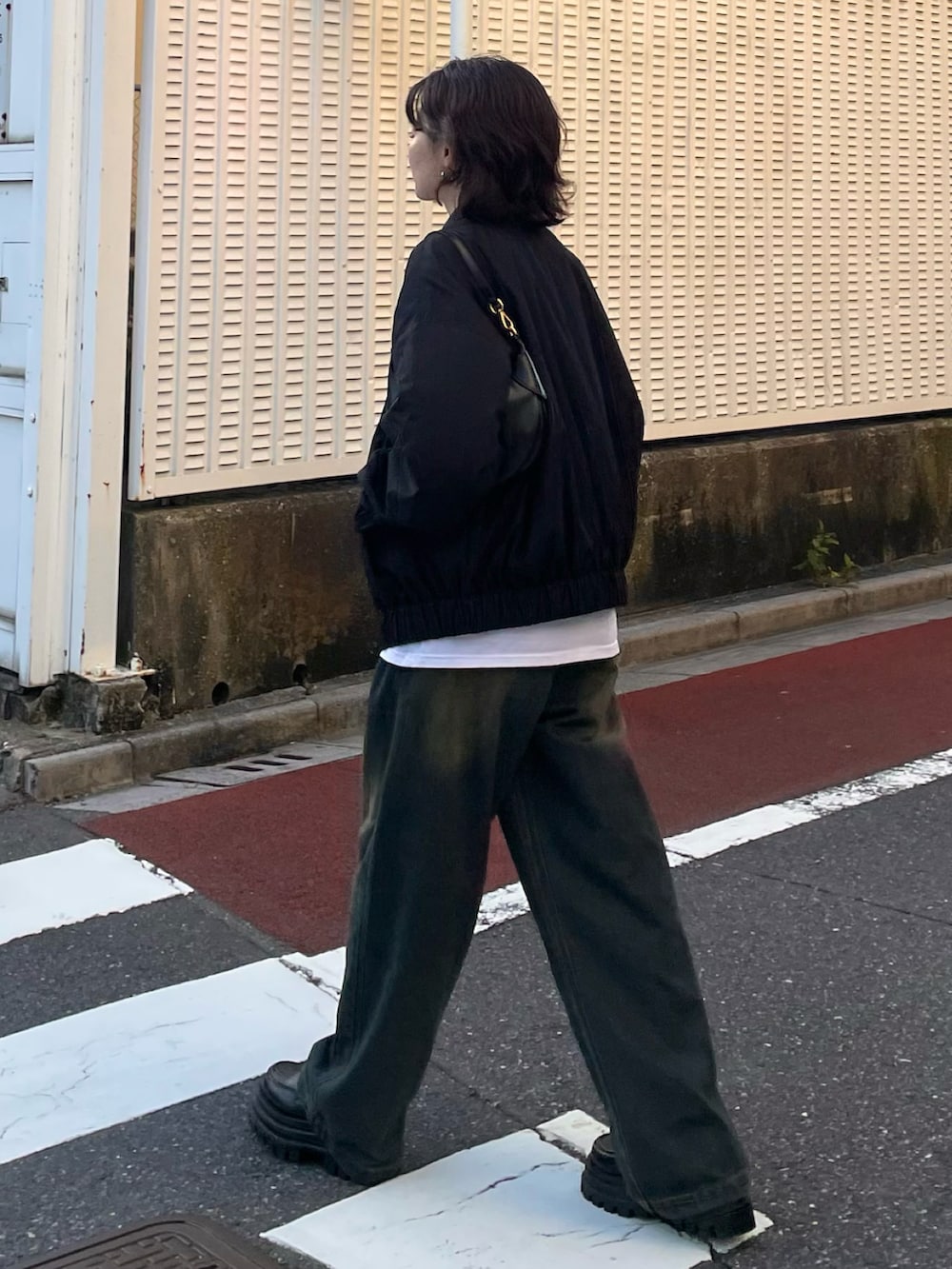 ブルー系のデニムパンツ、ブラック系のローファー、ブラック系のブルゾンを着用したレディースの秋コーディネートの2枚目の写真