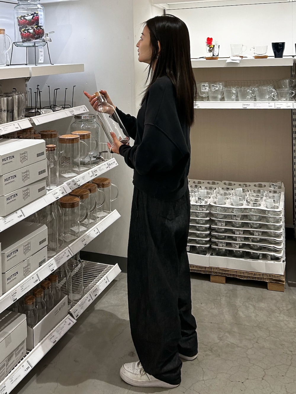 ブラック系のスウェット、ホワイト系のスニーカー、ブラック系のデニムパンツを着用したレディースの秋コーディネートの2枚目の写真