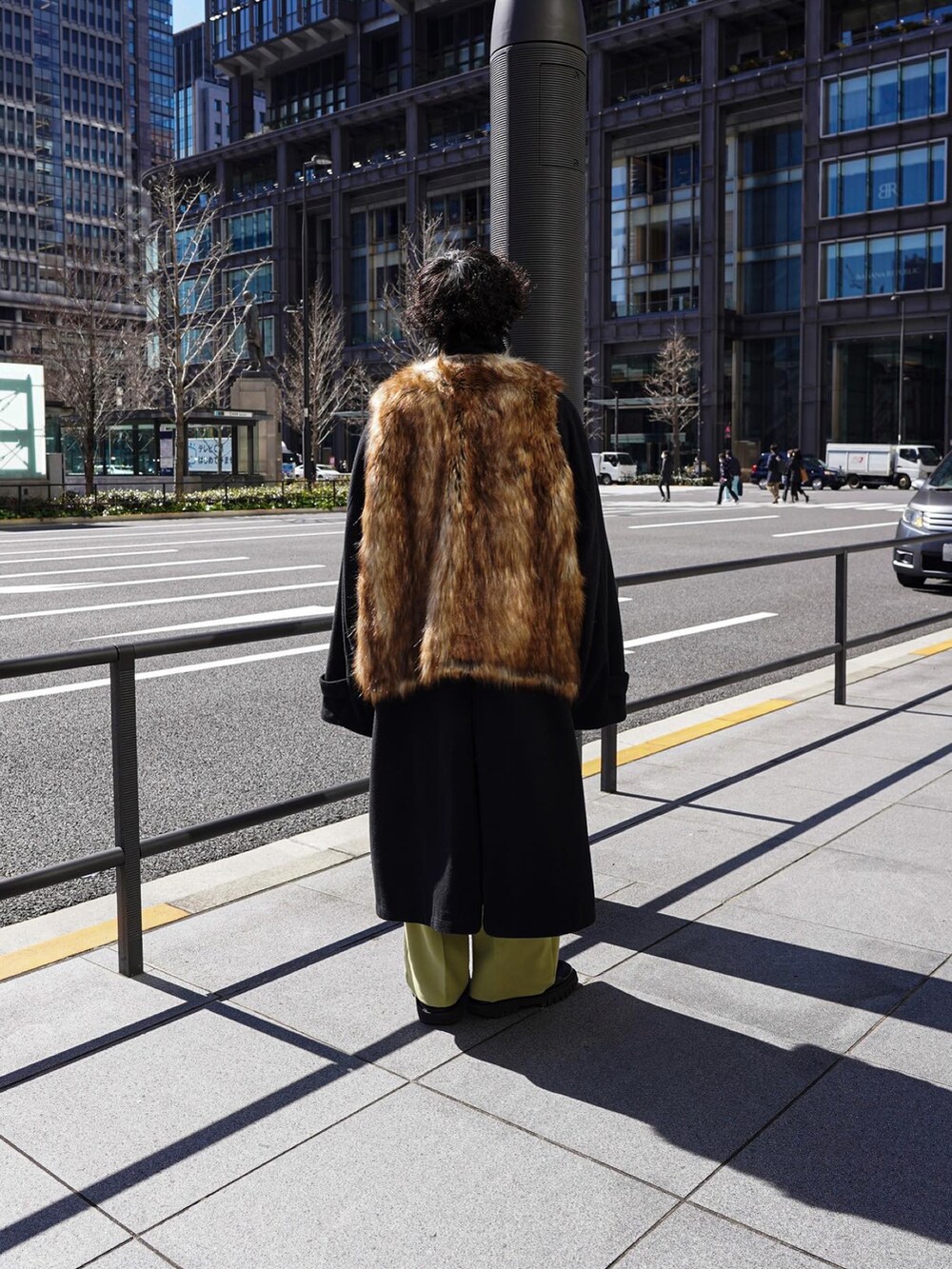 ブラウン系のベスト、ブラック系のステンカラーコートを着用したメンズの春コーディネートの4枚目の写真