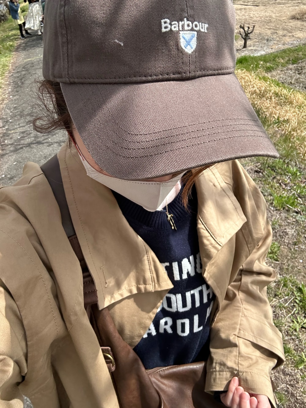 ベージュ系のトレンチコート、ブルー系のデニムパンツ、ブラウン系のショルダーバッグを着用したレディースの春コーディネートの2枚目の写真