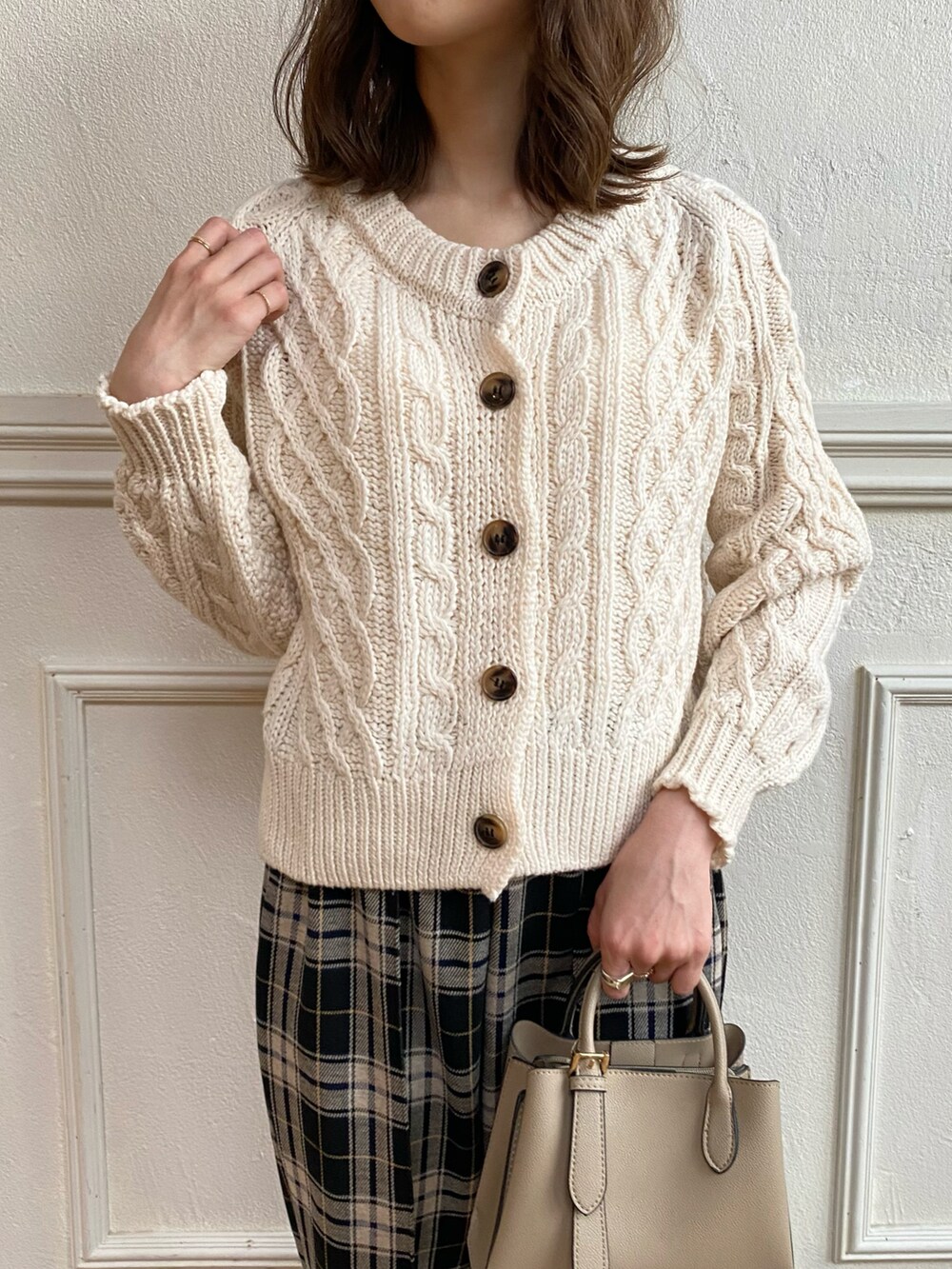 ベージュ系のハンドバッグ、ベージュ系のカーディガン/ボレロ、ブラック系のデニムパンツを着用したレディースの秋コーディネートの2枚目の写真