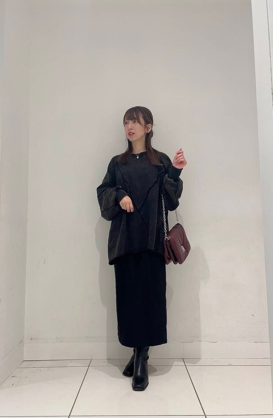 ブラック系のスカート、ブラック系のブーツ、レッド系のショルダーバッグを着用したレディースの秋コーディネートの2枚目の写真