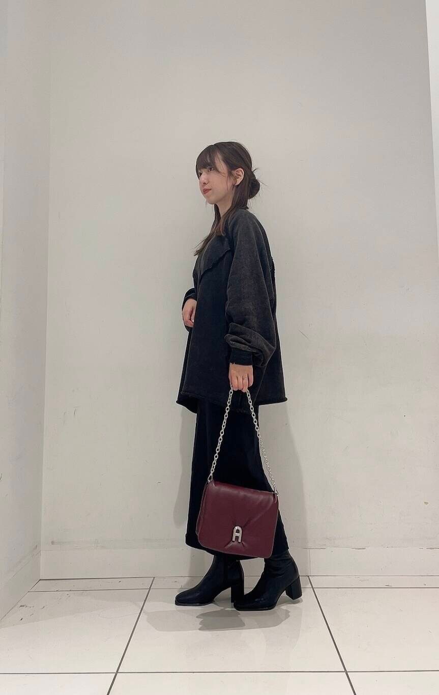 ブラック系のスカート、ブラック系のブーツ、レッド系のショルダーバッグを着用したレディースの秋コーディネートの3枚目の写真
