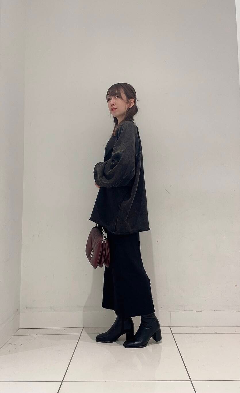 ブラック系のスカート、ブラック系のブーツ、レッド系のショルダーバッグを着用したレディースの秋コーディネートの4枚目の写真