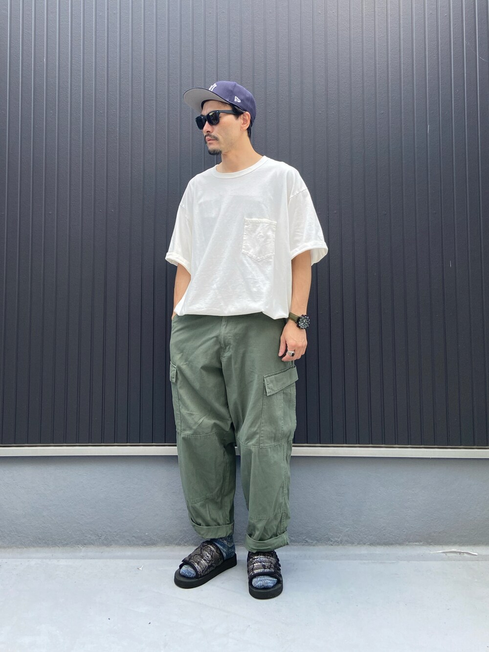 ホワイト系のTシャツ/カットソー、グリーン系のパンツ、ブラック系のシューズを着用したメンズの夏コーディネートの3枚目の写真