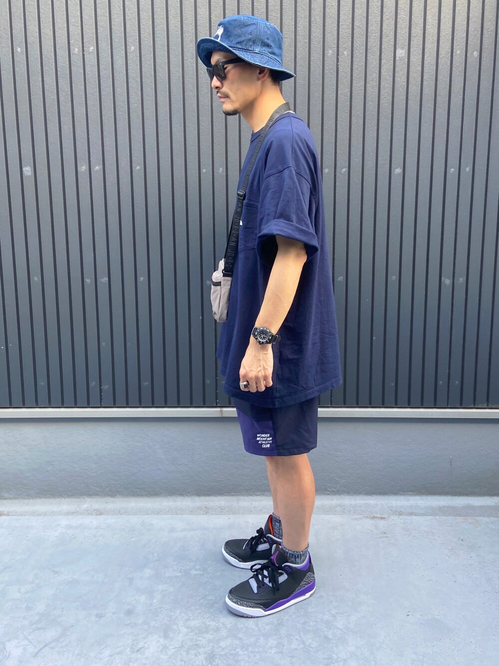 グレー系のバッグ、ブルー系のTシャツ/カットソー、ブルー系のパンツを着用したメンズの秋コーディネートの2枚目の写真