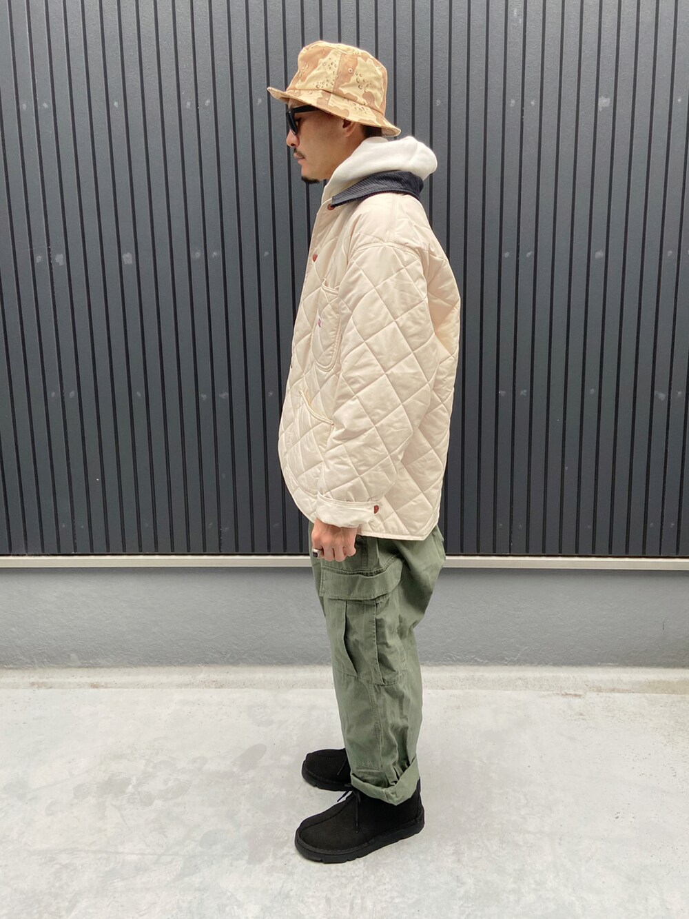 ホワイト系のカバーオール、ホワイト系のパーカー、グリーン系のパンツを着用したメンズの秋コーディネートの2枚目の写真