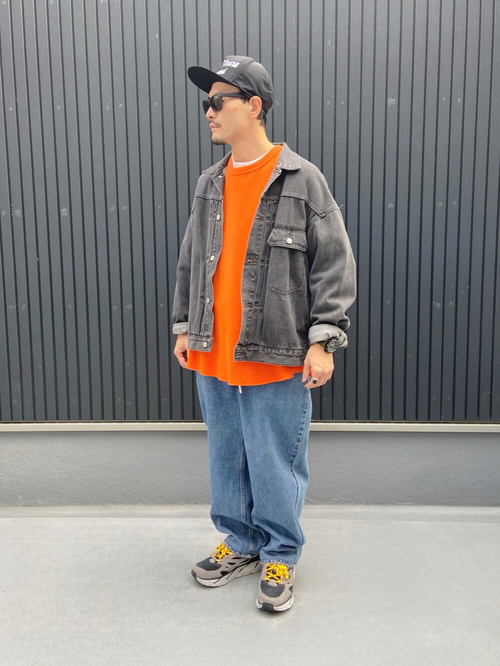グレー系のジャケット/アウター、オレンジ系のTシャツ/カットソー、ブルー系のデニムパンツを着用したメンズの秋コーディネートの3枚目の写真
