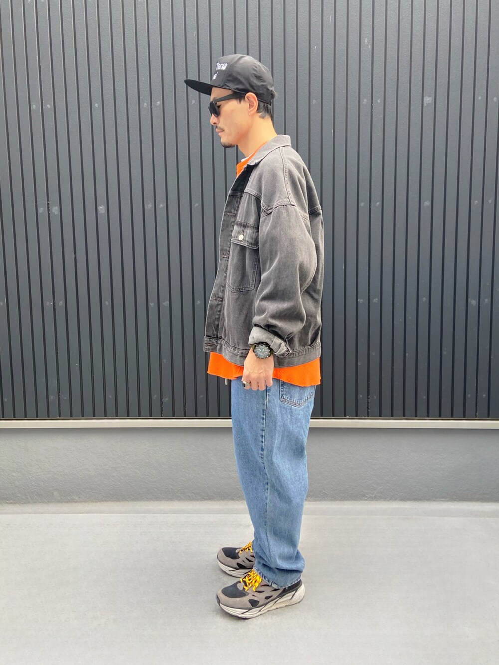 グレー系のジャケット/アウター、オレンジ系のTシャツ/カットソー、ブルー系のデニムパンツを着用したメンズの秋コーディネートの2枚目の写真